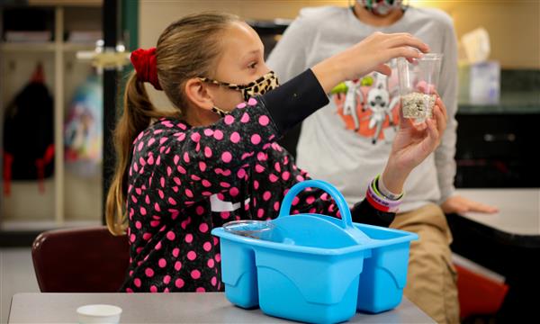 Girl holds up cup full of rocks